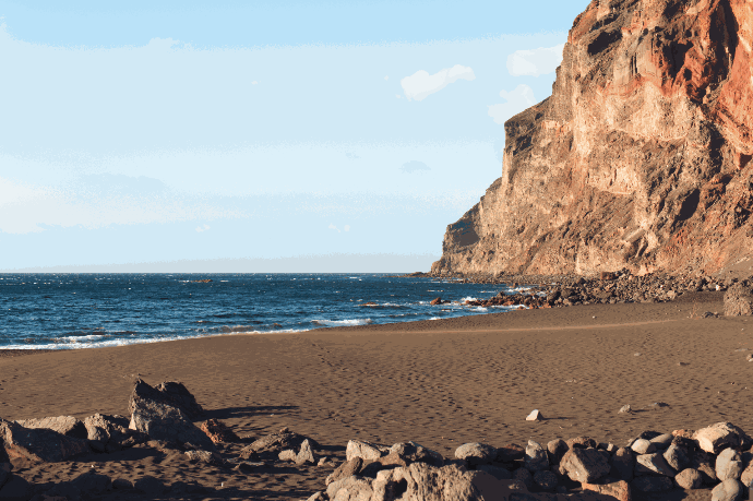 Playa de arena escondida al lado de una montaña donde no hay nadie